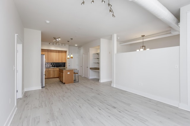 unfurnished living room with baseboards, light wood-style floors, and an inviting chandelier