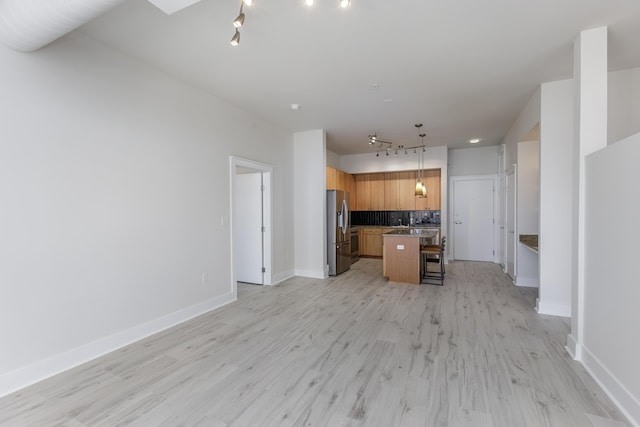 unfurnished living room featuring track lighting, light wood-type flooring, and baseboards