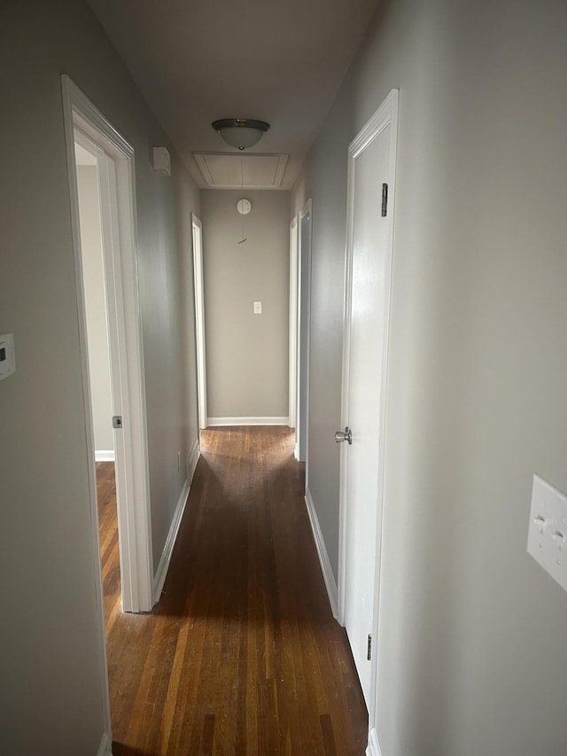 hall featuring attic access, baseboards, and wood finished floors