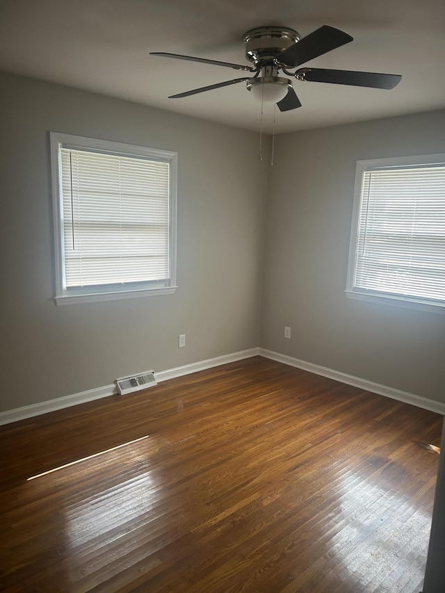 spare room featuring dark wood-style floors, visible vents, baseboards, and a ceiling fan