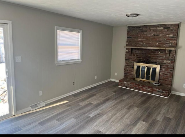 unfurnished living room with visible vents, a healthy amount of sunlight, wood finished floors, and a fireplace