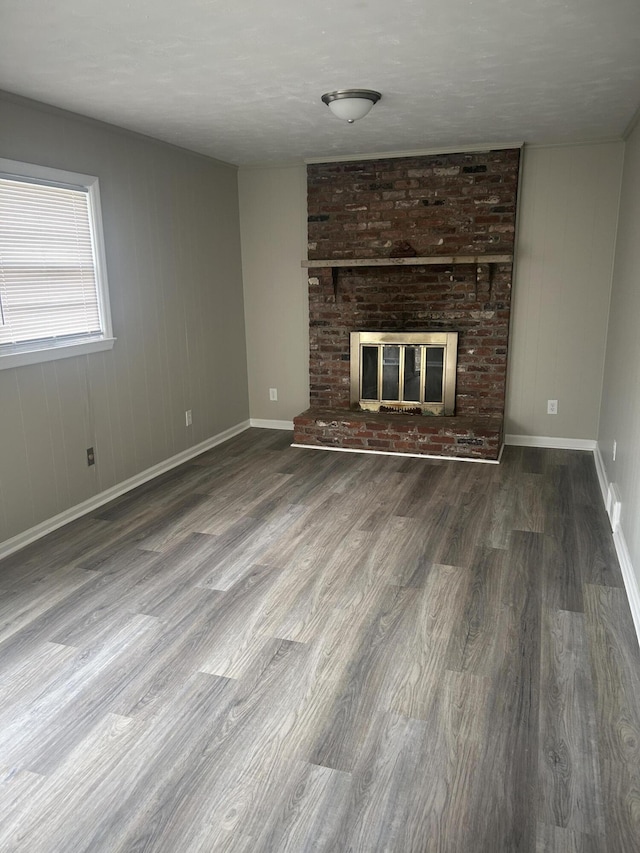 unfurnished living room with a fireplace, baseboards, and wood finished floors