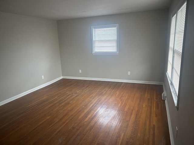 empty room featuring dark wood-style floors and baseboards