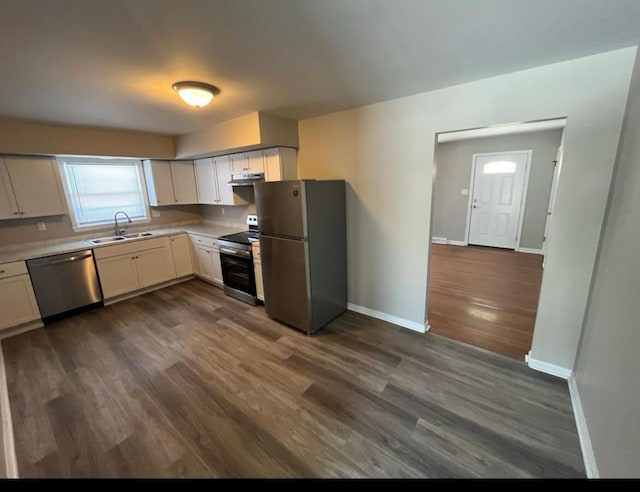 kitchen with under cabinet range hood, light countertops, dark wood-style floors, stainless steel appliances, and a sink