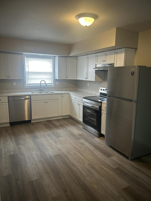 kitchen with dark wood finished floors, a sink, light countertops, under cabinet range hood, and appliances with stainless steel finishes