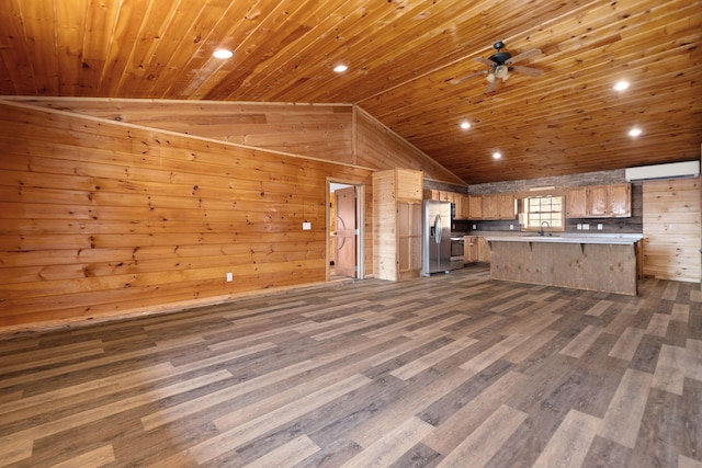 kitchen with wood walls, light countertops, lofted ceiling, stainless steel fridge, and a sink