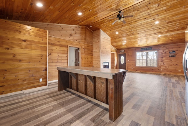 kitchen with light wood-style flooring, wood walls, wood ceiling, tile counters, and vaulted ceiling