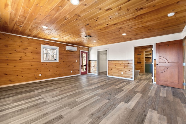 interior space featuring a wall mounted air conditioner, connected bathroom, wood finished floors, and wooden ceiling