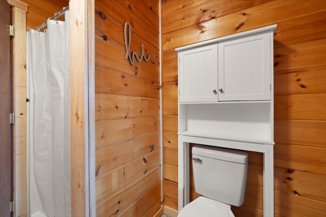 bathroom featuring wooden walls and toilet