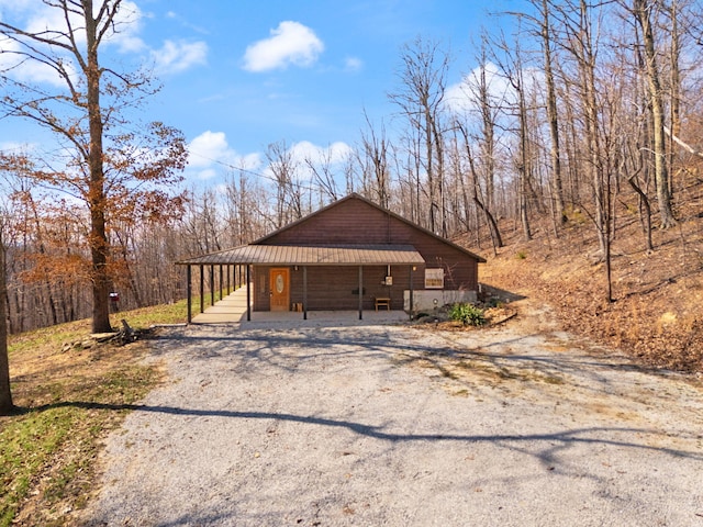 view of front of property featuring covered porch, driveway, and metal roof