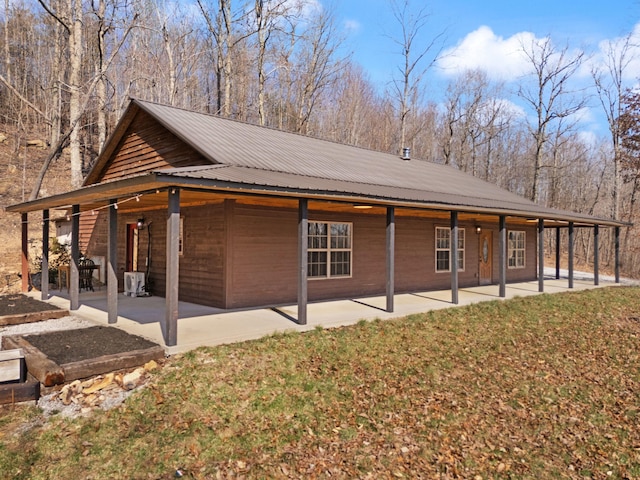 view of side of property with a yard, a patio area, and metal roof