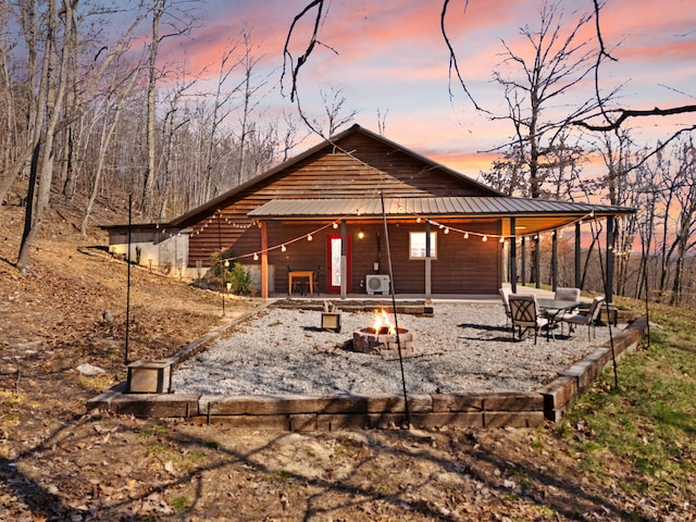 rear view of house featuring a patio, metal roof, and an outdoor fire pit