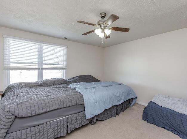 carpeted bedroom featuring a textured ceiling and ceiling fan