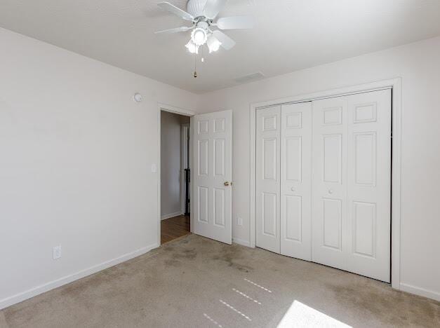 unfurnished bedroom featuring baseboards, carpet floors, a closet, and ceiling fan