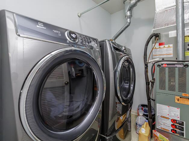 washroom featuring heating unit, laundry area, and washing machine and clothes dryer