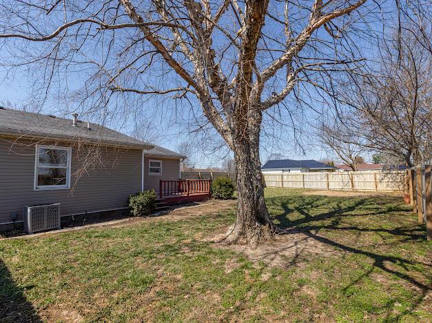 view of yard with a wooden deck, central air condition unit, and fence