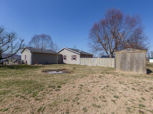 view of yard with an outdoor structure, a shed, and fence