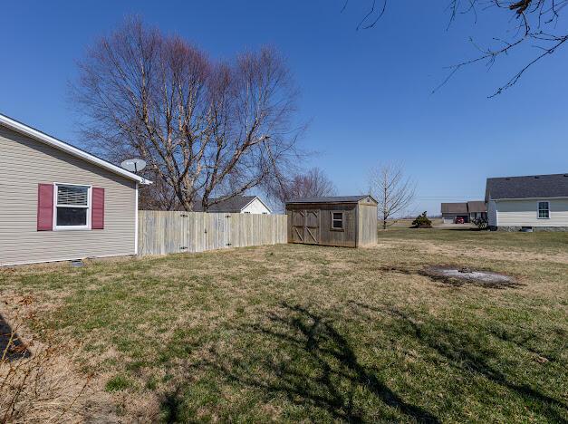 view of yard featuring an outbuilding, a storage shed, and fence