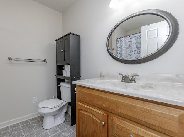 bathroom with toilet, vanity, and baseboards