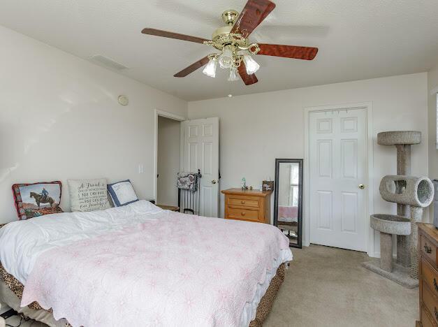 bedroom with visible vents, light carpet, and a ceiling fan