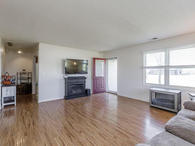 living area featuring visible vents, a fireplace, light wood-type flooring, and baseboards