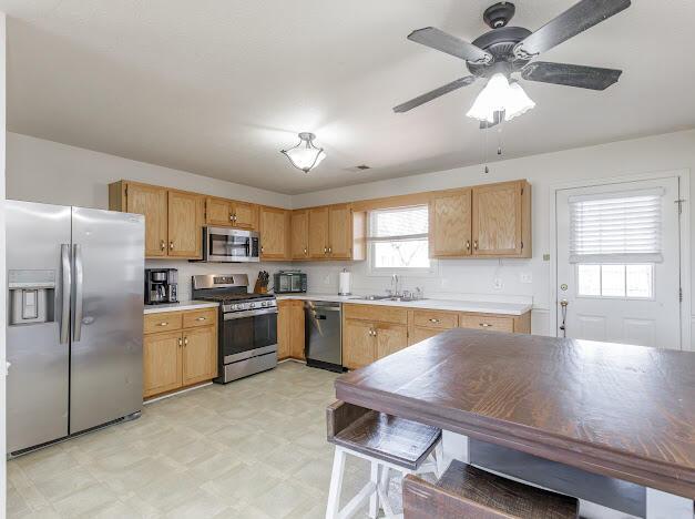 kitchen featuring a ceiling fan, a sink, appliances with stainless steel finishes, light countertops, and light floors