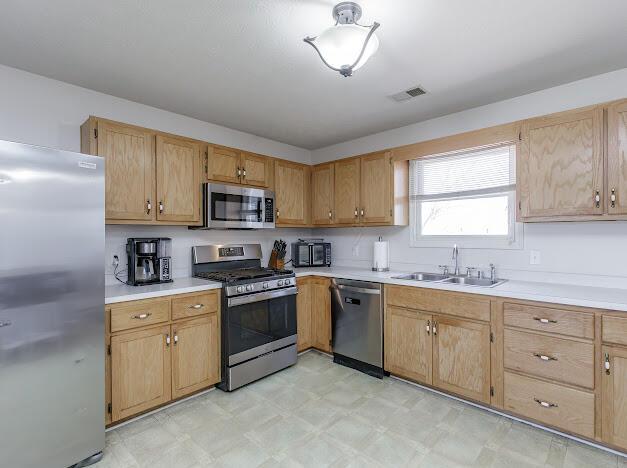 kitchen featuring visible vents, a sink, appliances with stainless steel finishes, light countertops, and light floors