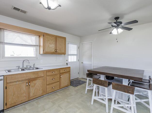 kitchen with dishwashing machine, light floors, visible vents, a sink, and light countertops