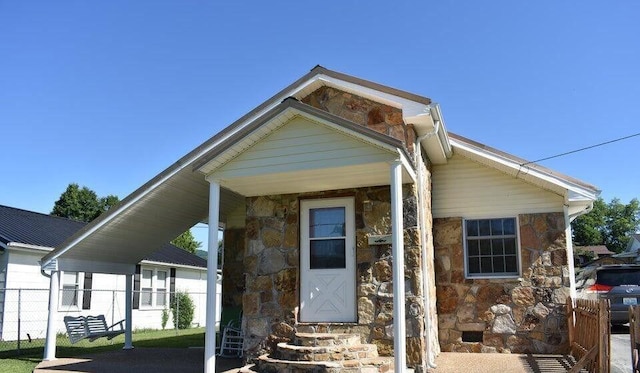 view of front of property with stone siding, entry steps, and fence