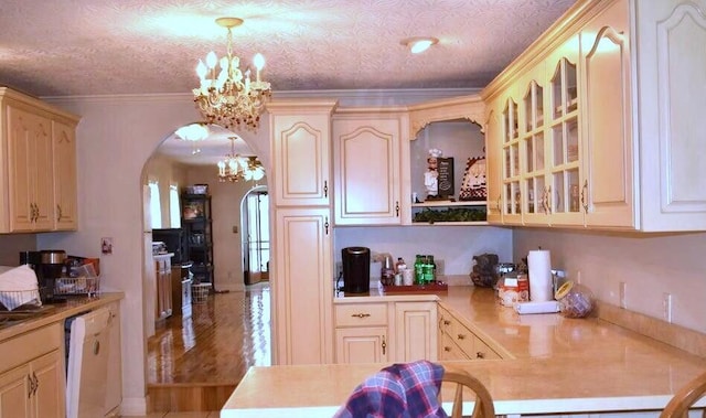 kitchen with arched walkways, crown molding, white dishwasher, a chandelier, and hanging light fixtures