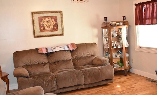 living room with light wood-style flooring, baseboards, and visible vents