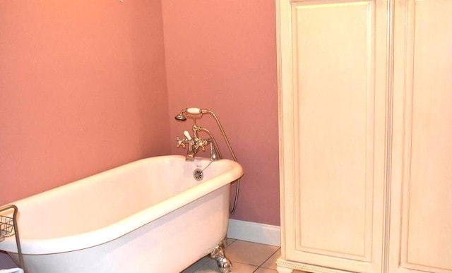 bathroom featuring tile patterned floors, a soaking tub, and baseboards