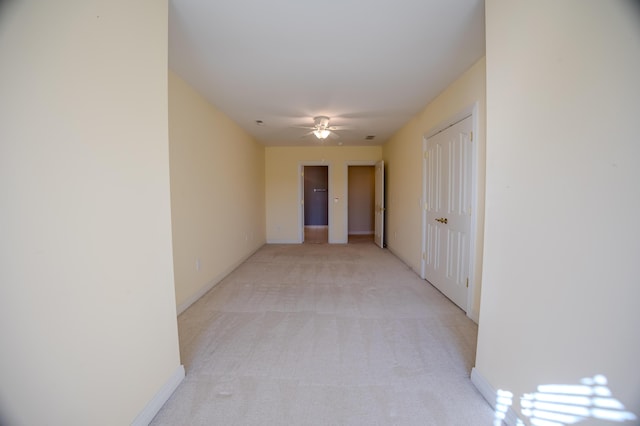 hall featuring baseboards and light colored carpet