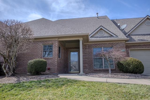 ranch-style home featuring brick siding, a shingled roof, a garage, and a front yard