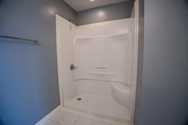 bathroom with tile patterned floors, baseboards, and walk in shower