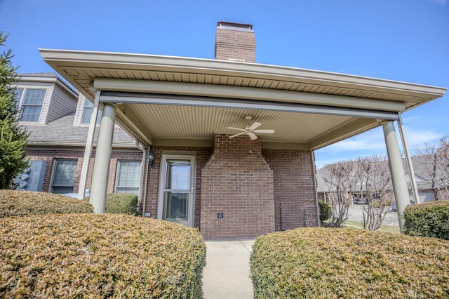 entrance to property featuring a ceiling fan, brick siding, and a chimney