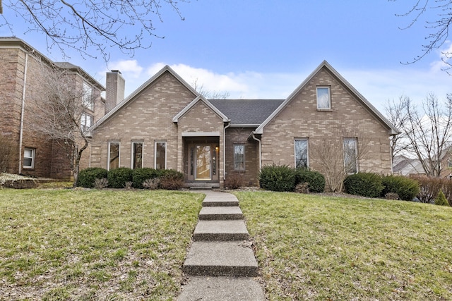 traditional-style home with brick siding, a chimney, and a front lawn