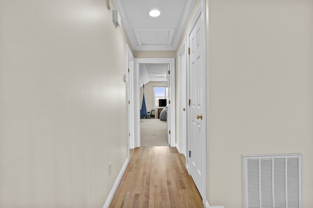 hall featuring visible vents, light wood-style flooring, attic access, and baseboards