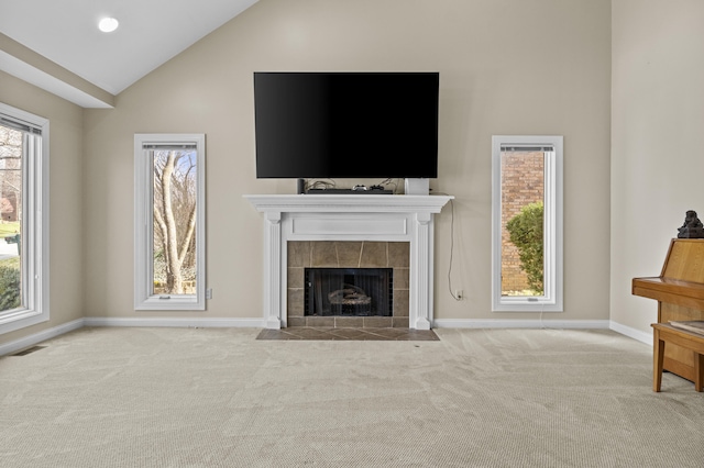 unfurnished living room featuring visible vents, baseboards, a tiled fireplace, carpet floors, and high vaulted ceiling