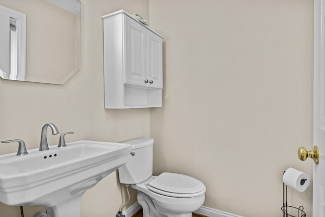 bathroom featuring toilet, baseboards, and a sink