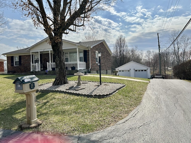 view of front of house with an outbuilding, a front yard, a porch, a detached garage, and brick siding