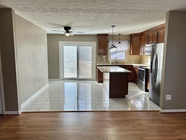 kitchen with a center island, ceiling fan, light wood-style flooring, stainless steel appliances, and a sink