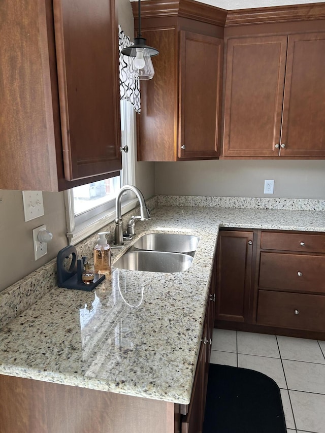 kitchen with light tile patterned flooring, decorative light fixtures, light stone countertops, and a sink