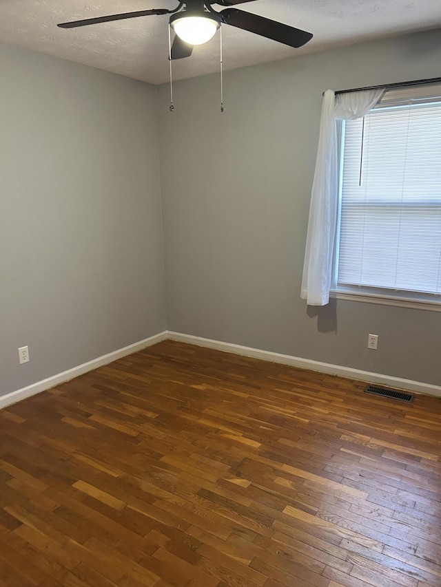 empty room featuring visible vents, baseboards, a ceiling fan, and wood-type flooring