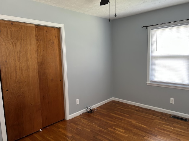 unfurnished bedroom with visible vents, baseboards, wood finished floors, a closet, and a textured ceiling