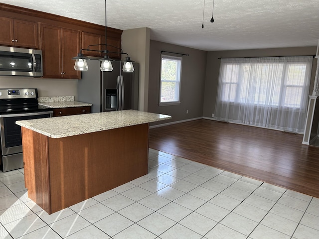 kitchen with a kitchen island, light tile patterned flooring, stainless steel appliances, a textured ceiling, and open floor plan