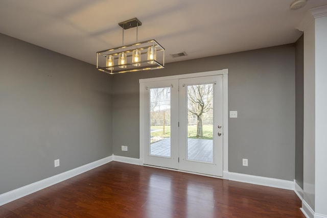 interior space with visible vents, baseboards, a notable chandelier, and wood finished floors