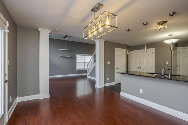 kitchen with baseboards, ornate columns, dark wood-style flooring, a sink, and pendant lighting