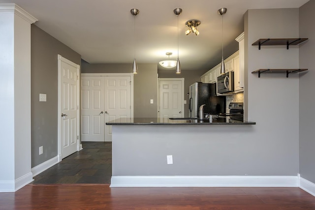 kitchen featuring dark wood-style floors, baseboards, appliances with stainless steel finishes, and a peninsula