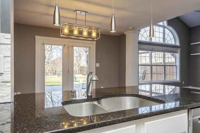 kitchen with a sink, a wealth of natural light, and dark stone countertops